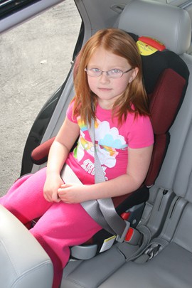 At a safety fair in Peoria in 2009, then 5-year-old Destinee Tellef demonstrates how a booster seat helps position a seat belt on a child.