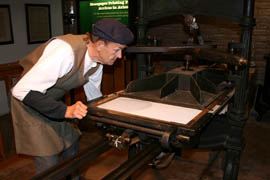 A worker operates a printing press at Tubac Presidio State Historic Park.