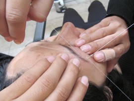 Juana Gutierrez threads the eyebrows of Pampha Tamang at s.h.a.p.e.s Brow Bar in Desert Sky Mall in Phoenix.