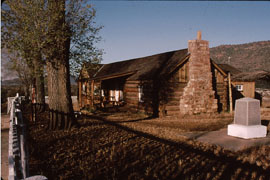 Building #1 at the Fort Apache site, Log Cabin, looking west, with replica historic fencing and Cibecue Battle monument.