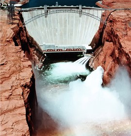 Water released from Lake Powell creates a rainbow over the Colorado River at the Glen Canyon Dam. The government has experimented with water releases from the dam to help restore the health of the river downstream.