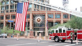 An American flag hangs from a fire truck's ladder outside Phoenix City Hall on Tuesday morning. A memorial ceremony was held inside the atrium shortly afterward.