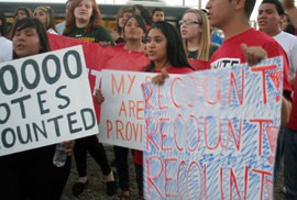 Protesters outside the Maricopa County Recorder's early tabulation center Wednesday said they're angry because of the amount of uncounted ballots. Faith Mendoza (middle) held a sign that read 