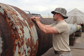 A volunteer from the Arizona Air National Guard helps scrape rust from the last gun barrel from the USS Arizona.
