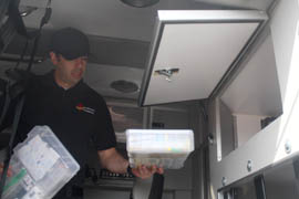 A technician with Southwest Ambulance loads medications into a temperature-controlled box inside an ambulance.