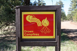 A sign urges visitors to fully extinguish campfires in the Coconino National Forest.