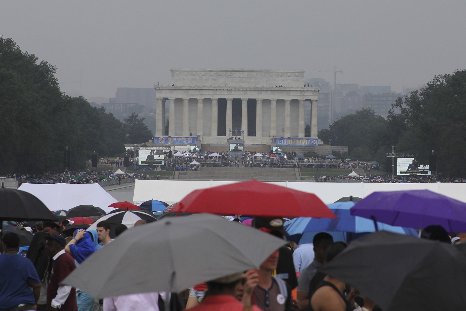 Thousands gathered around the Reflecting Pool under a rainy Washington sky to hear speeches from the Lincoln Memorial to mark the 50th anniversary of the historic March on Washington.