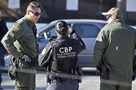 Border Patrol agents and a CBP Field Operations Officer talk at a border crossing in San Ysidro, Calif.