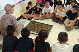 Moses Thompson, Manzo Elementary School's counselor and its ecology system designer and builder, uses seed-starter blocks, each with 20 sections, to show first-graders how to count by 100s.