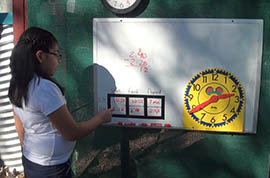 Fifth-grader Aaraceli Fuentes demonstrates how third-and fifth-graders record time worked on Manzo Elementary School's compost bins to learn how to calculate elapsed time.