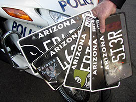 Walter Olsen, a motorcycle officer with the Phoenix Police Department, displays several altered Arizona Cardinals plates.