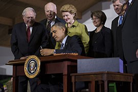 President Barack Obama signs the Agricultural Act of 2014 at Michigan State University in East Lansing, Mich. Among the many provisions in the nearly $1 trillion bill are cuts to the food stamp program, but they will not be felt by Arizona recipients.