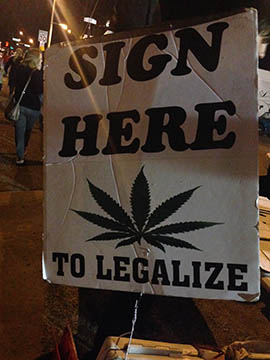 A sign seeks signatures on a petition to have a referendum in November on legalizing the recreational use of marijuana in Arizona.