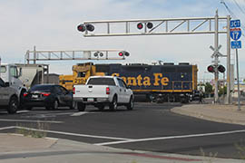 A train crosses a road along Grand Avenue in Phoenix.