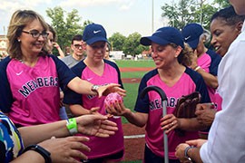 Former Arizona Rep. Gabrielle Giffords grabs a softball autographed by breast-cancer survivors before throwing out the ceremonial first pitch in the Sixth Annual Congressional Women's Softball game with women reporters.
