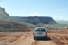 A vehicle crosses the construction site during a media tour of repairs to U.S. 89. The original road, buried by the landslide, can be seen at left.