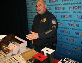 Sgt. David Lake with Phoenix Police Department displays counterfeit merchandise at a news conference Friday.