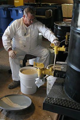 Rick Neiner Sr., a technician at Gilbert’s Household Hazardous Waste Facility, pours recycled latex paint into 5-gallon containers that are offered for free.