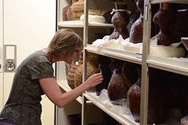 Suzanne Eckert, head of collections at the Arizona State Museum, with shelves full of baskets that are part of the museum's collection.