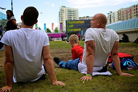 People from all over the world gather on the grass lawn outside Olympic Park just to watch for athletes passing by and enjoy the nice weather in London.